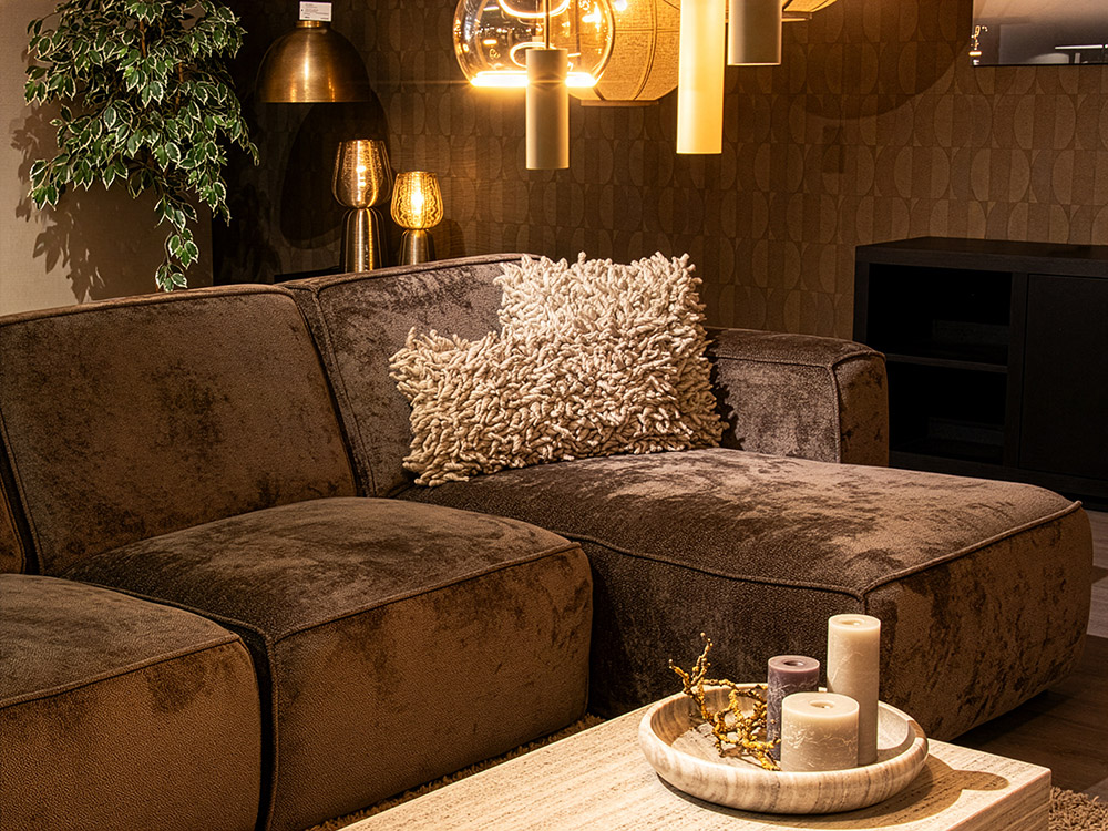 Gezellige woonkamer met bruine hoekbank, hanglampen, kussens en woonaccessoires bij Straluma