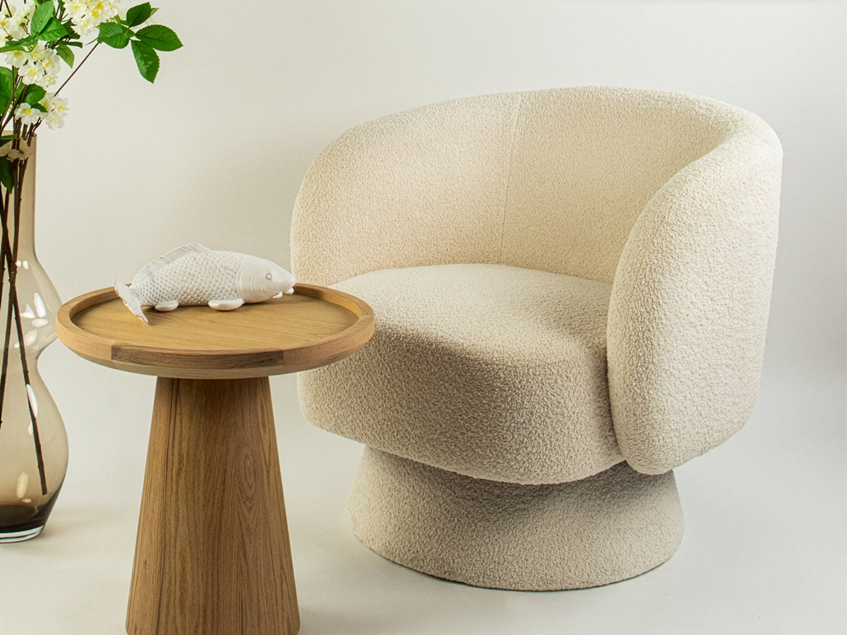 Beige bouclé fauteuil met houten bijzettafel en decoratieve vis in modern interieur