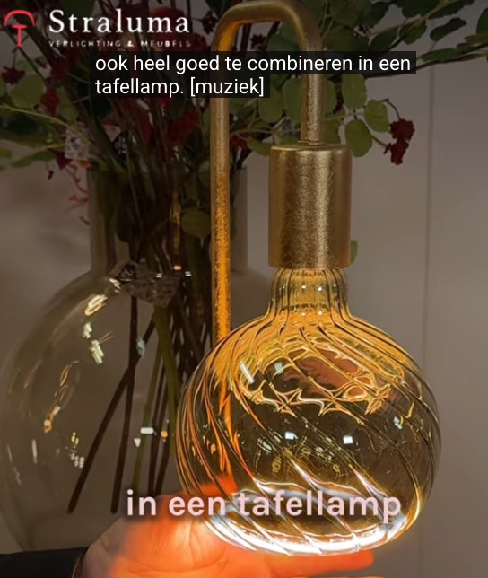 Goudkleurige tafellamp met een brandende SEGULA Floating LED lichtbron met gedraaid glasdesign, gepresenteerd bij Straluma als verlichtingstrend voor 2026.