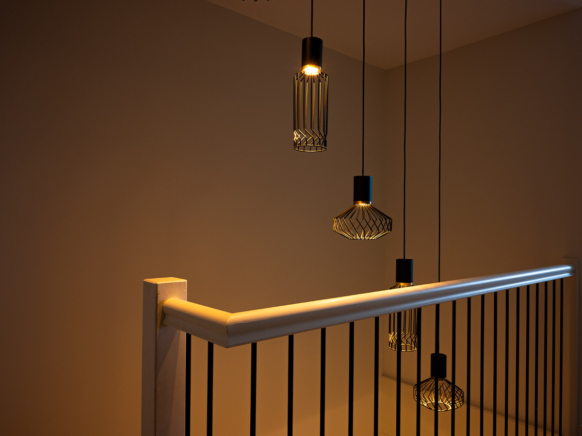 Moderne hanglampen met warm licht boven een trap, professioneel toegepast door Straluma voor sfeervolle trapverlichting.