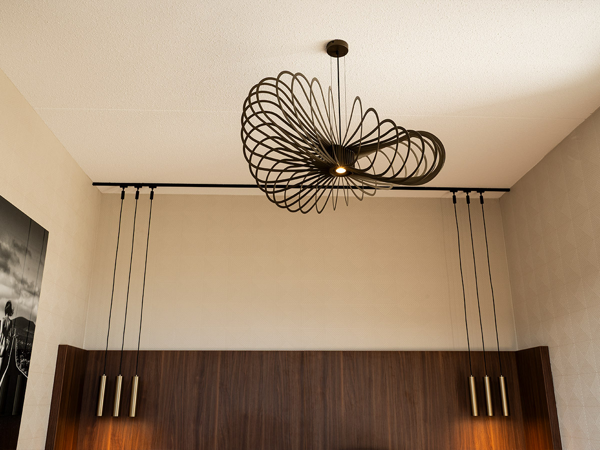 Bijzondere design plafondlamp met speels lijnenspel en hangende accentverlichting, toegepast in een interieur door Straluma.