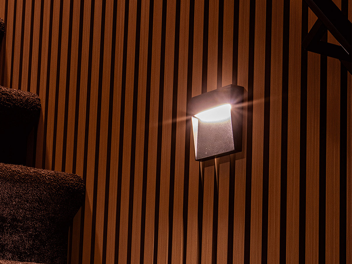 Moderne wandlamp van Straluma langs een houten lattenwand in Het Wapen van Rhoon.