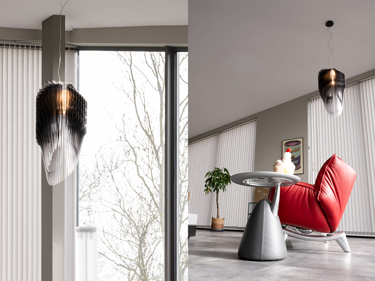 Design hanglamp in modern penthouse met grote raampartijen en rode fauteuil