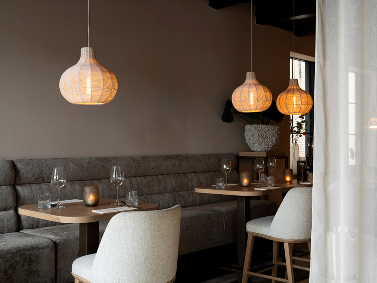 Straluma projectverlichting met rotan hanglampen boven restauranttafels in een sfeervolle seafoodbar